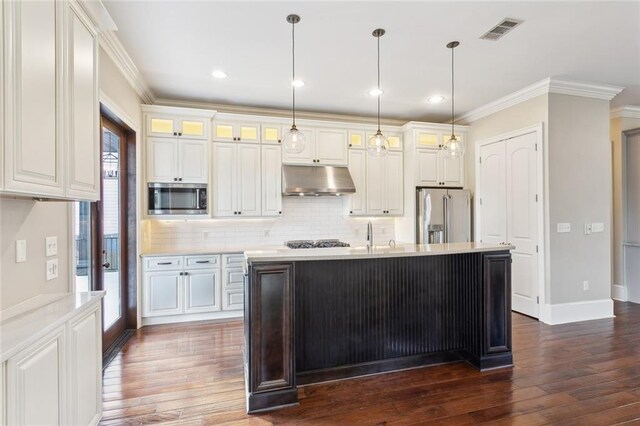 kitchen with a center island with sink, stainless steel appliances, pendant lighting, crown molding, and white cabinets