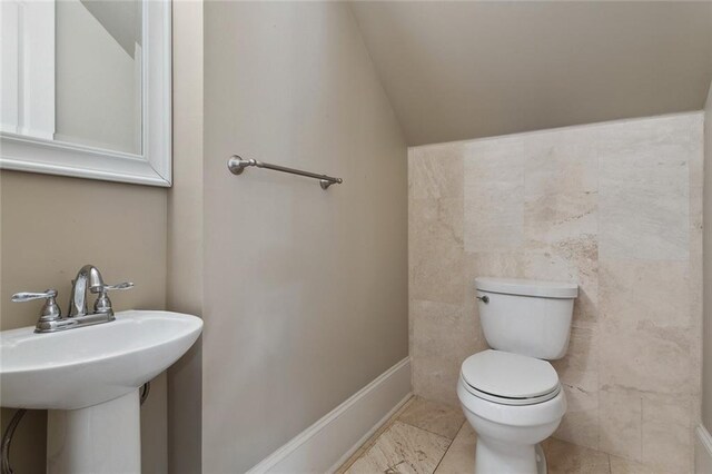 bathroom featuring toilet, vaulted ceiling, tile patterned floors, and sink