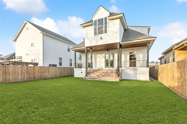 back of property with ceiling fan, a yard, and a porch