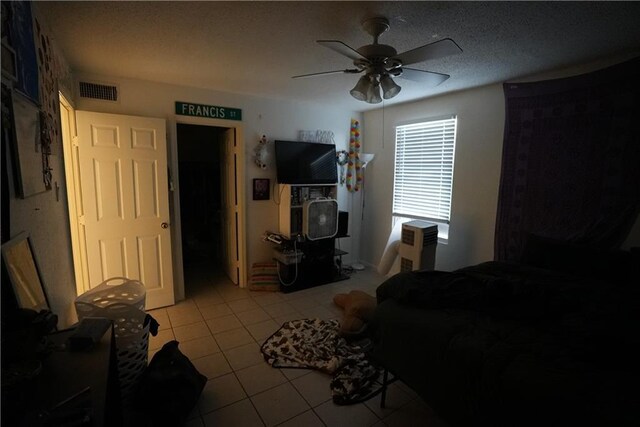 living room with ceiling fan, a textured ceiling, and light tile patterned floors