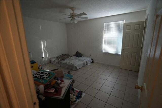 unfurnished bedroom with ceiling fan, a textured ceiling, and light tile patterned floors