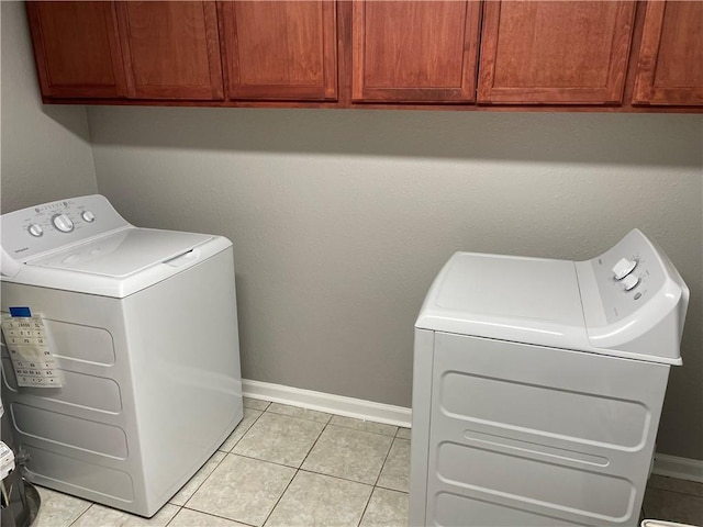 laundry area with separate washer and dryer, light tile patterned floors, and cabinets