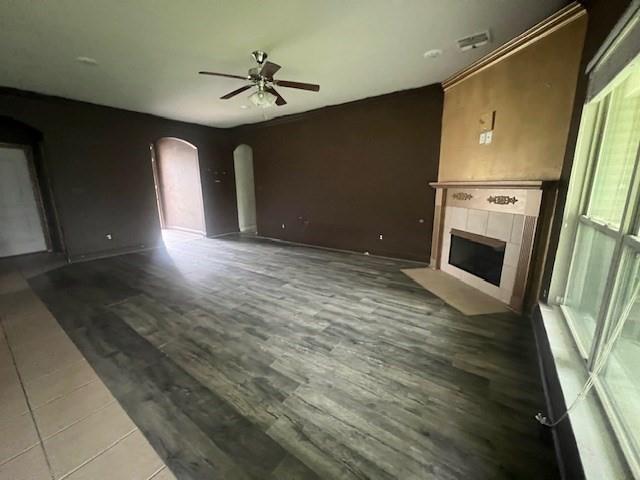 unfurnished living room with ceiling fan, a tile fireplace, and hardwood / wood-style flooring