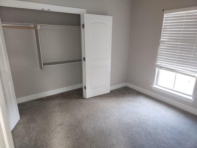 unfurnished bedroom with a closet and dark colored carpet