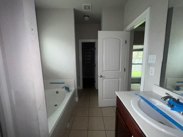 bathroom featuring tile patterned floors, vanity, and a tub to relax in