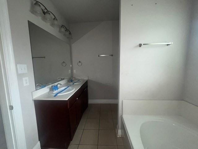 bathroom with a tub, vanity, and tile patterned flooring