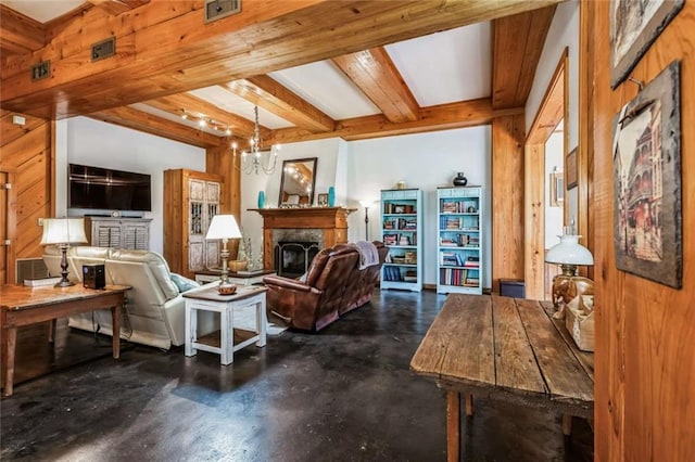 living room featuring an inviting chandelier, wood walls, a premium fireplace, concrete flooring, and beam ceiling