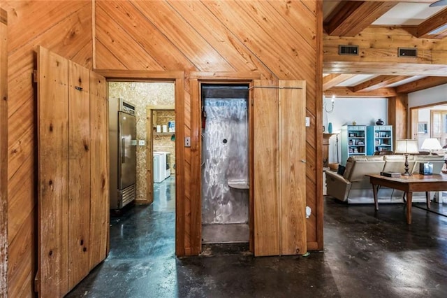 hallway featuring washer / clothes dryer, beam ceiling, and wooden walls