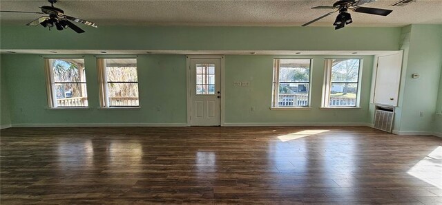 unfurnished living room with a textured ceiling, ceiling fan, and dark hardwood / wood-style floors