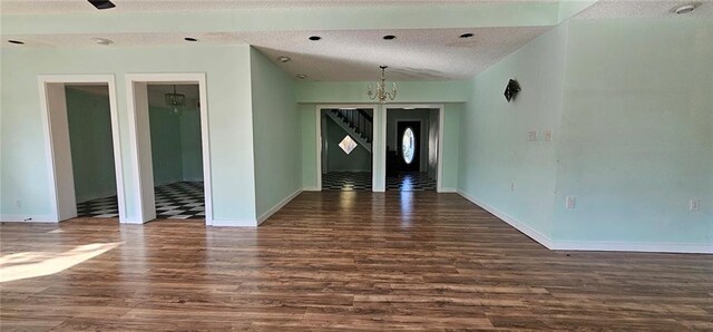 unfurnished room featuring a textured ceiling, dark wood-type flooring, and a chandelier