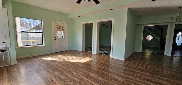 spare room with a textured ceiling, dark wood-type flooring, and ceiling fan with notable chandelier