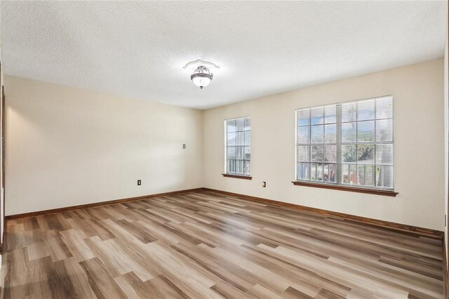 empty room featuring a textured ceiling and light hardwood / wood-style floors