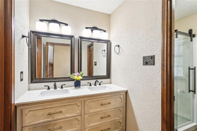 bathroom with an enclosed shower, vanity, and a textured ceiling