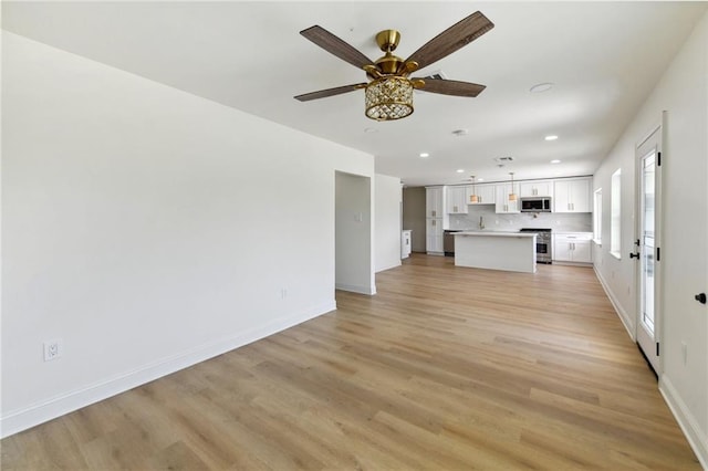 unfurnished living room featuring ceiling fan and light wood-type flooring