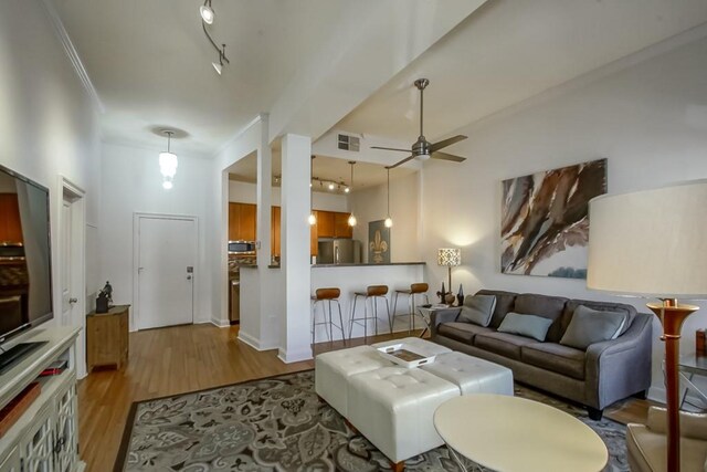 living room featuring ceiling fan, rail lighting, crown molding, and light hardwood / wood-style floors