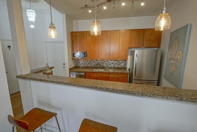 kitchen with decorative backsplash, decorative light fixtures, kitchen peninsula, and stainless steel appliances