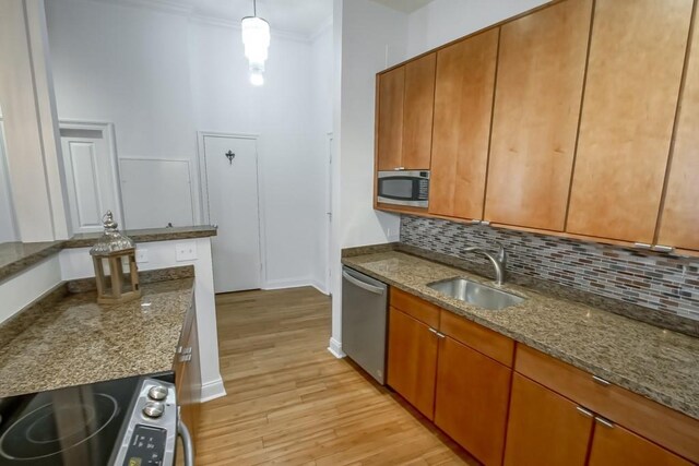 kitchen with light stone countertops, appliances with stainless steel finishes, hanging light fixtures, and sink