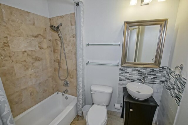 full bathroom with toilet, shower / bathtub combination with curtain, vanity, and tile walls