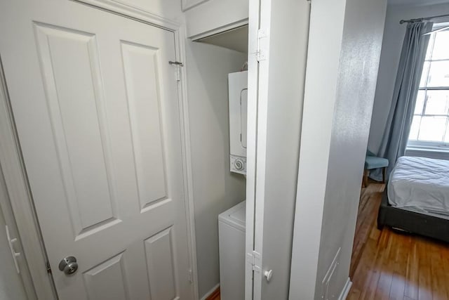 laundry area featuring hardwood / wood-style flooring and stacked washing maching and dryer