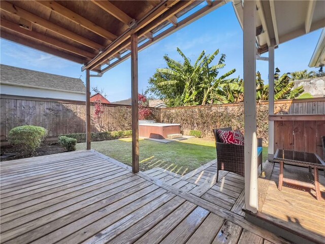 deck with a hot tub and a yard