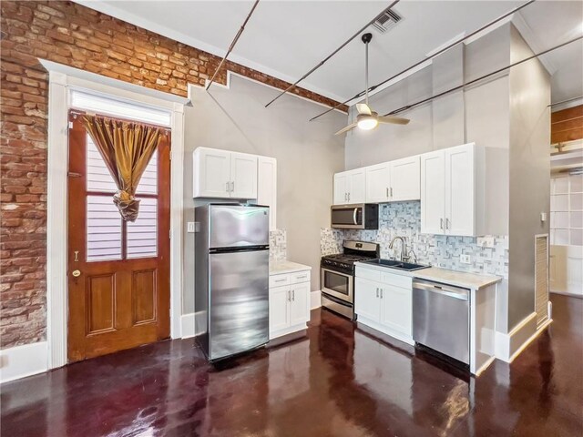 kitchen with tasteful backsplash, a towering ceiling, white cabinetry, hanging light fixtures, and appliances with stainless steel finishes