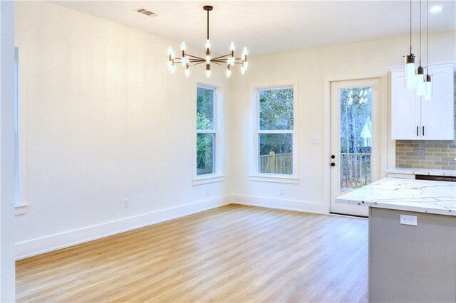 unfurnished dining area featuring a chandelier and light hardwood / wood-style flooring