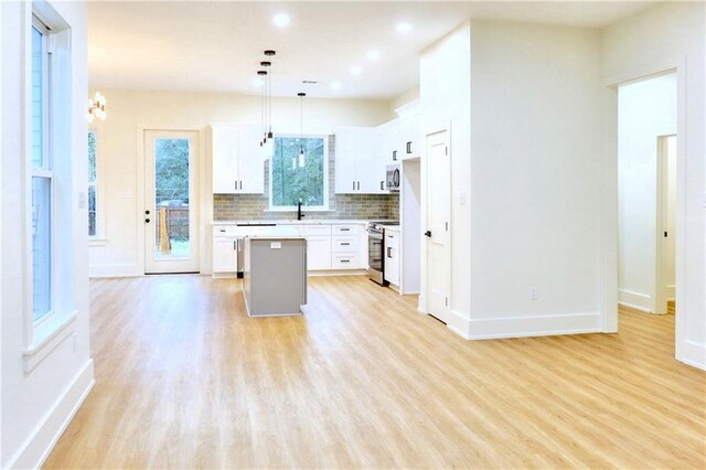 kitchen with appliances with stainless steel finishes, a center island, decorative light fixtures, white cabinetry, and decorative backsplash