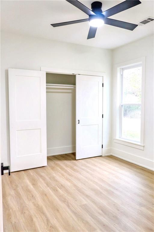 unfurnished bedroom with ceiling fan, light hardwood / wood-style flooring, and a closet