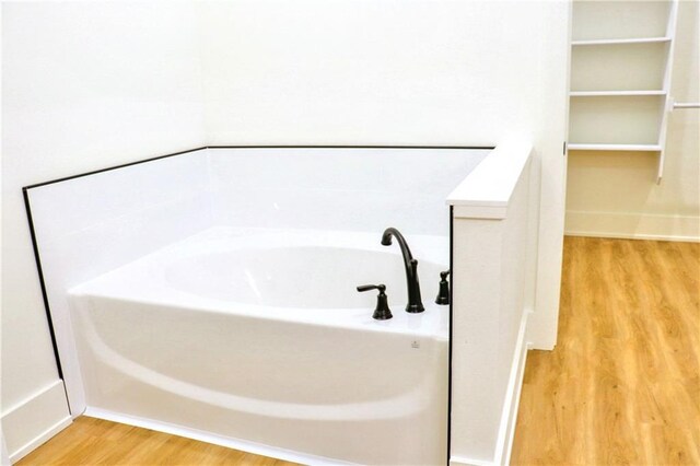 bathroom with wood-type flooring and a bathtub