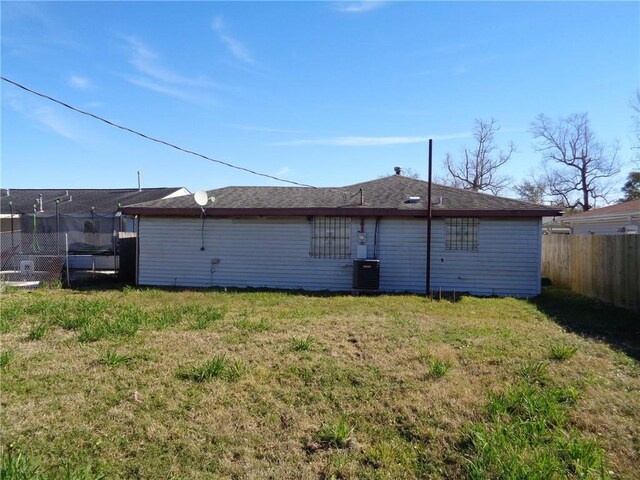 rear view of property with a lawn and central air condition unit