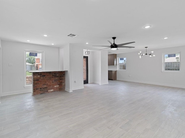 unfurnished living room featuring light hardwood / wood-style floors and ceiling fan with notable chandelier