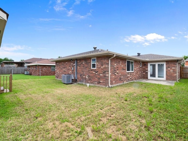 rear view of house with cooling unit, a yard, and a patio area