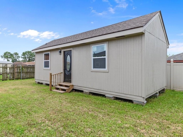 back of house with an outbuilding and a lawn