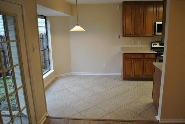 kitchen featuring decorative light fixtures, light tile patterned floors, and appliances with stainless steel finishes