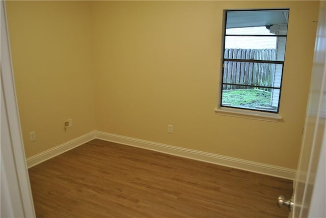 spare room featuring wood-type flooring and plenty of natural light