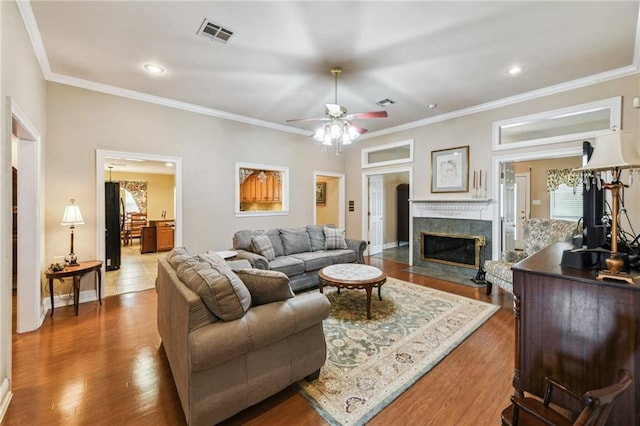 living room with ceiling fan, a fireplace, crown molding, and hardwood / wood-style floors