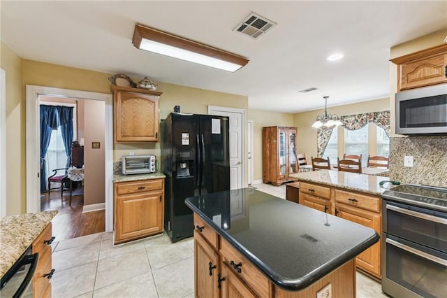 kitchen featuring a kitchen island, stainless steel appliances, hanging light fixtures, a chandelier, and light tile patterned floors