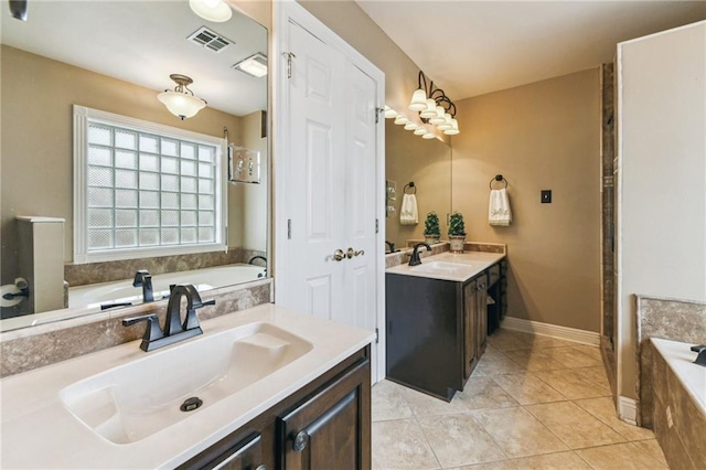 bathroom with tile patterned flooring, tiled tub, and vanity