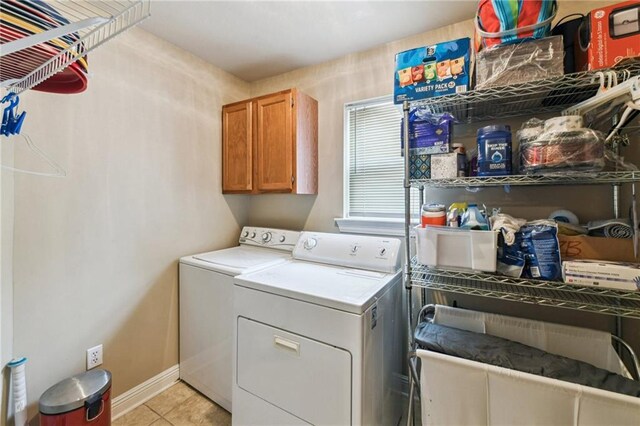 laundry room featuring cabinets, light tile patterned flooring, and washer and clothes dryer