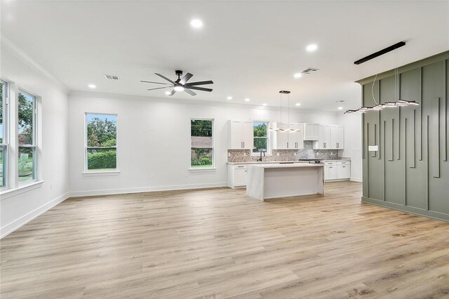 kitchen featuring pendant lighting, white cabinetry, backsplash, light hardwood / wood-style floors, and a kitchen island