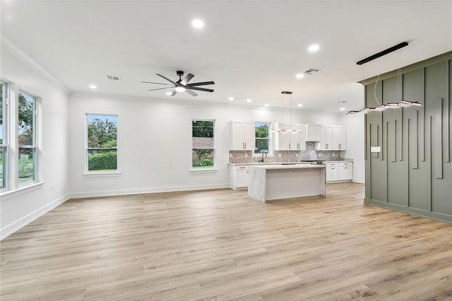 kitchen featuring a center island, tasteful backsplash, light countertops, visible vents, and open floor plan