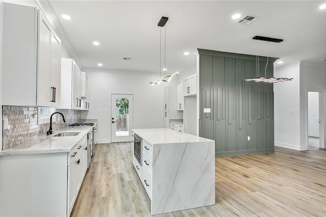 kitchen with light stone counters, visible vents, backsplash, and a sink