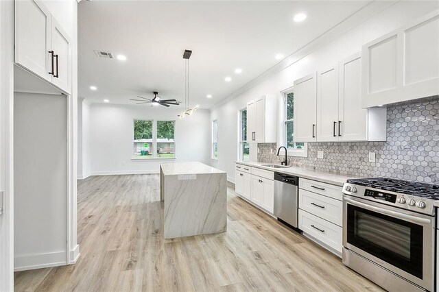 kitchen featuring white cabinetry, stainless steel appliances, sink, and a kitchen island