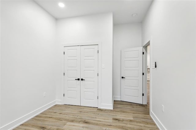 unfurnished bedroom featuring light wood-style floors, baseboards, a closet, and recessed lighting