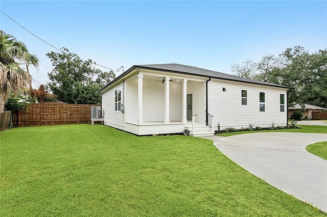 rear view of property featuring entry steps, a yard, central AC unit, and fence