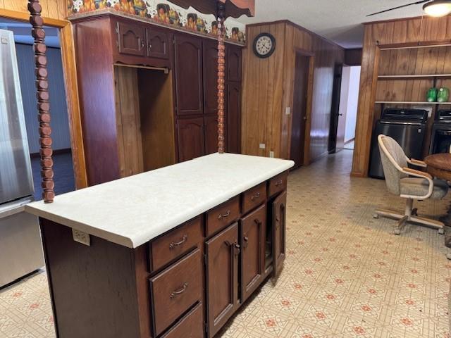 kitchen with washer and clothes dryer, dark brown cabinets, and wood walls