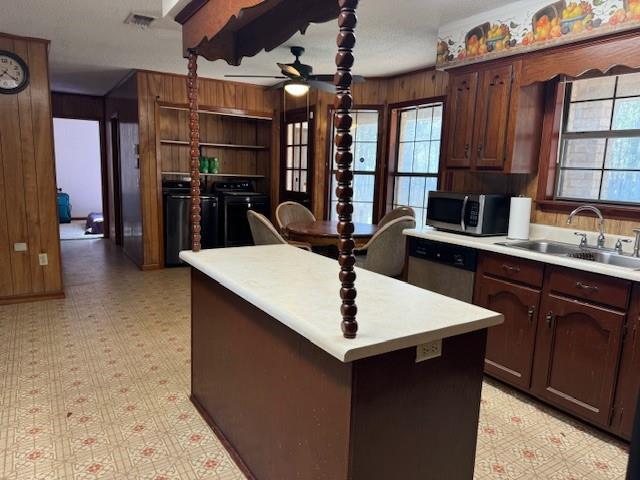 kitchen featuring ceiling fan, a kitchen island, sink, dark brown cabinetry, and stainless steel appliances