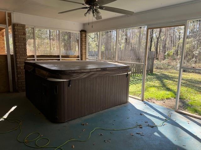 unfurnished sunroom with ceiling fan, a hot tub, and plenty of natural light