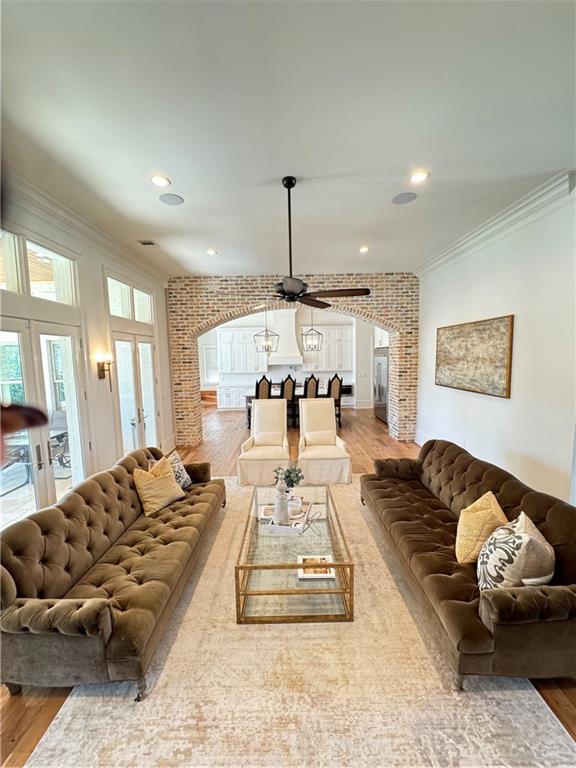 living room with hardwood / wood-style floors, ceiling fan, brick wall, french doors, and crown molding