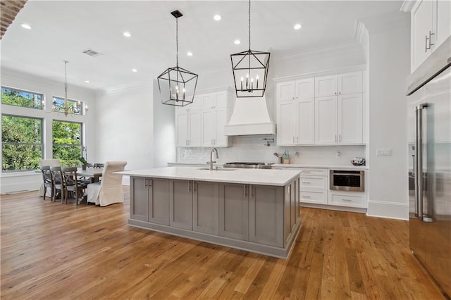 kitchen with decorative light fixtures, premium range hood, and white cabinets